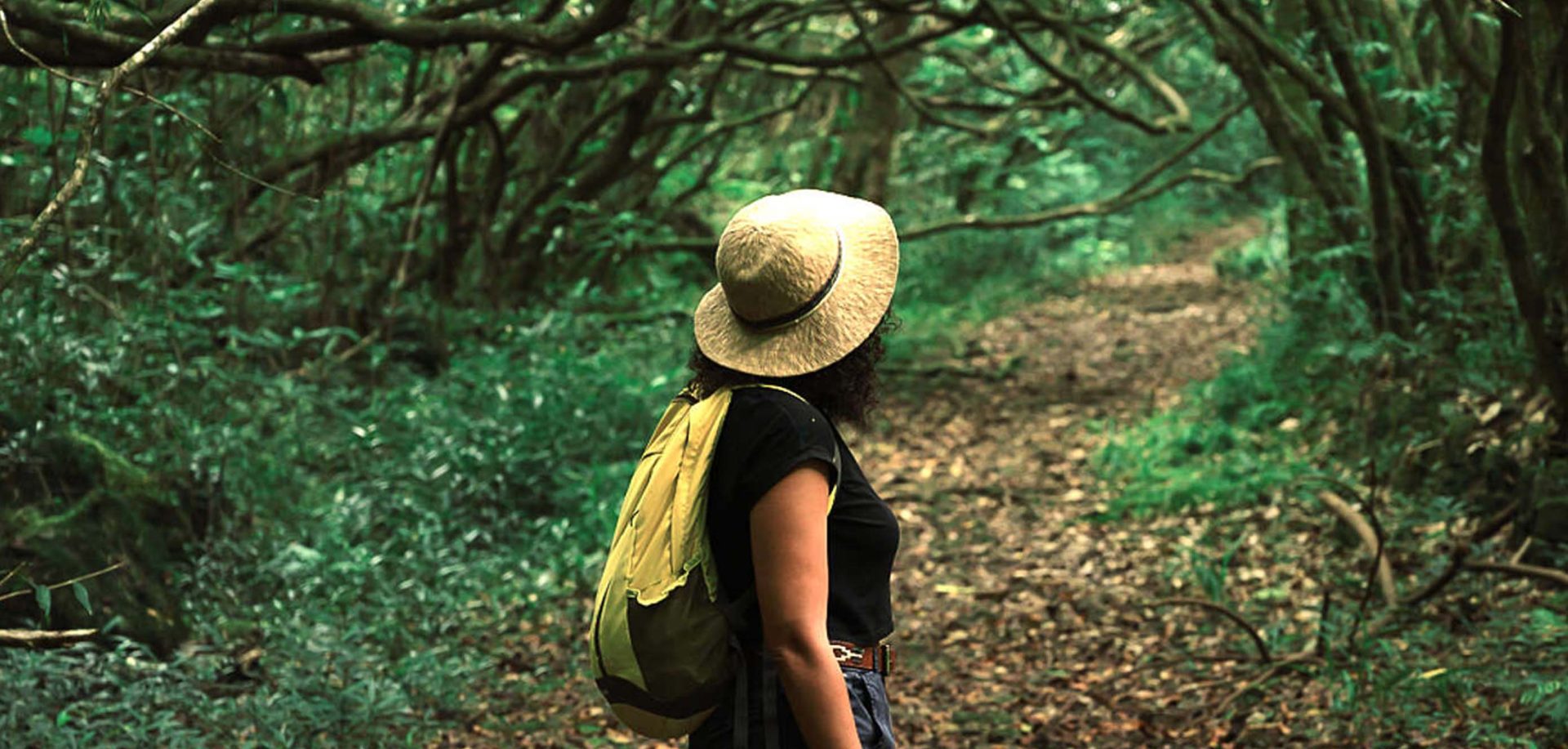 Mujer con sombrero caminando por el bosque - Bienestar en el este de Reunión