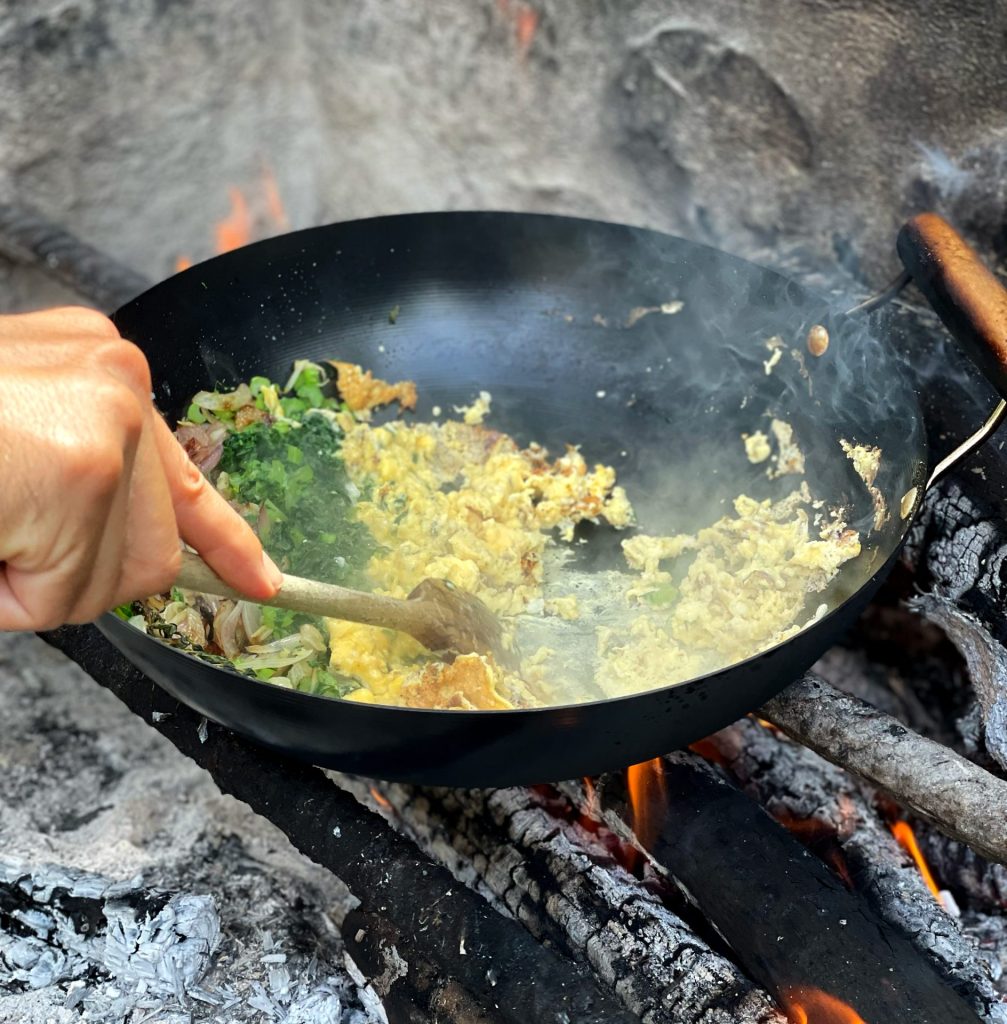 Preparing rice heated over a wood fire for a picnic.