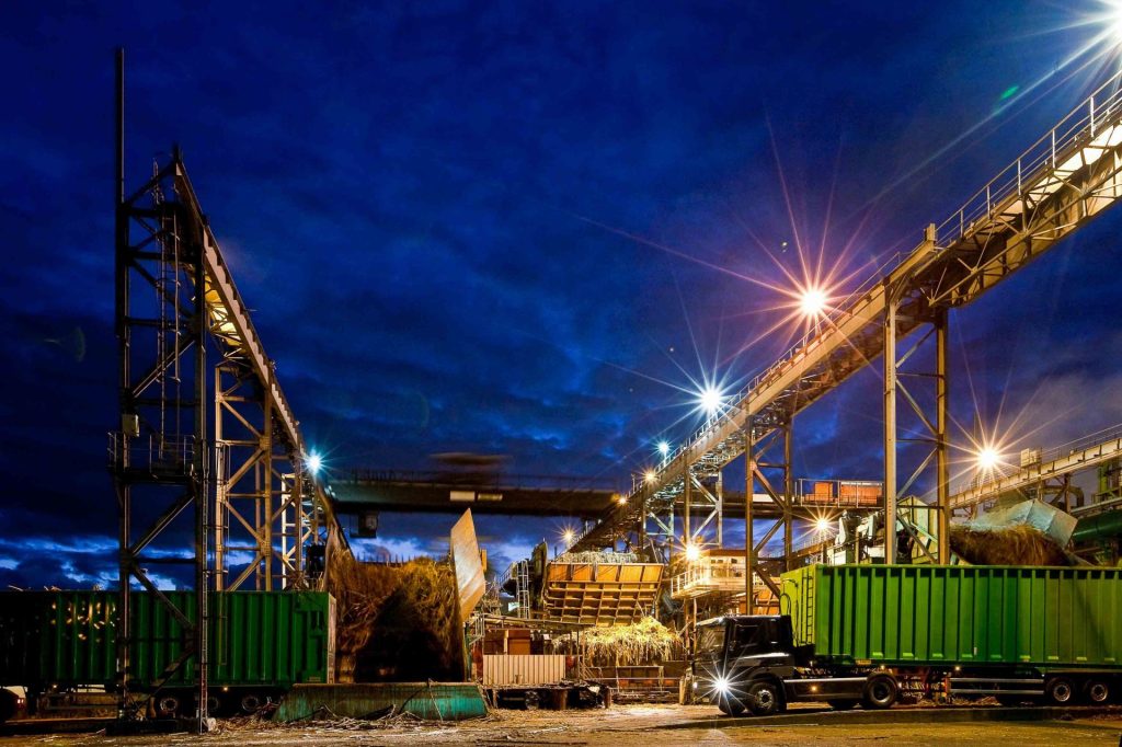 Usine de Bois rouge éclairée de nuit avec des camion de canne à sucre