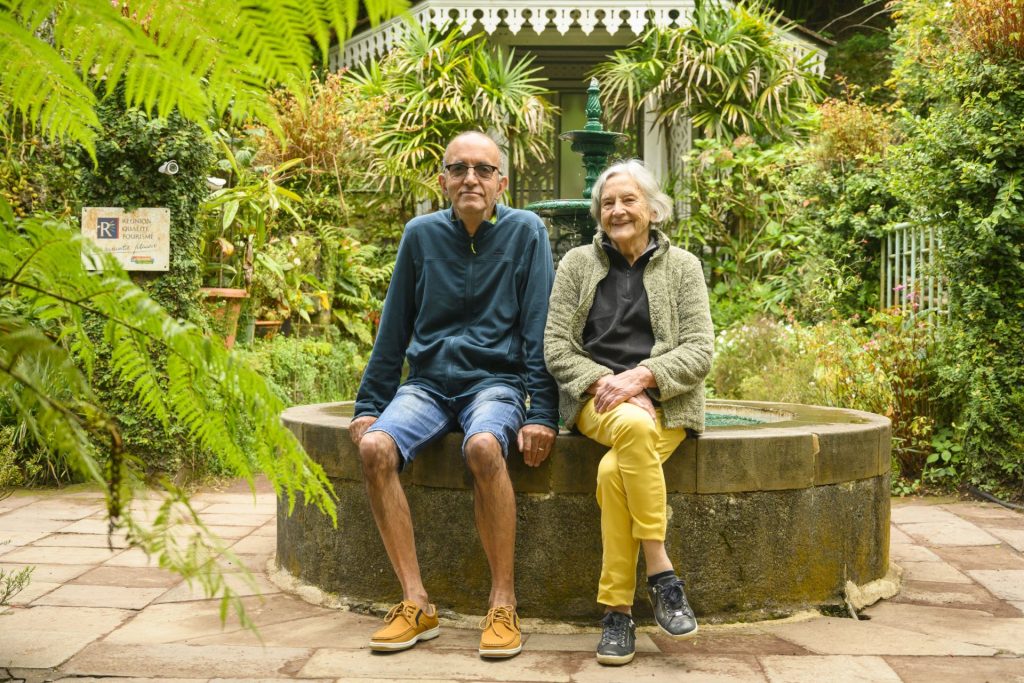 Maison Folio à Salazie façade case créole et jardin deux personnes assises près d'une fontaine