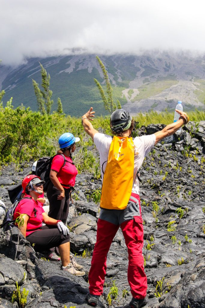 Una guía trasera y dos excursionistas sentados en un antiguo flujo de lava.